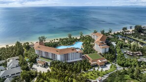 Un resort con varias edificaciones, una piscina y vista al océano.