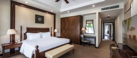 Habitación de hotel con una cama grande, un escritorio, una silla, un ventilador de techo y un cuadro en la pared.