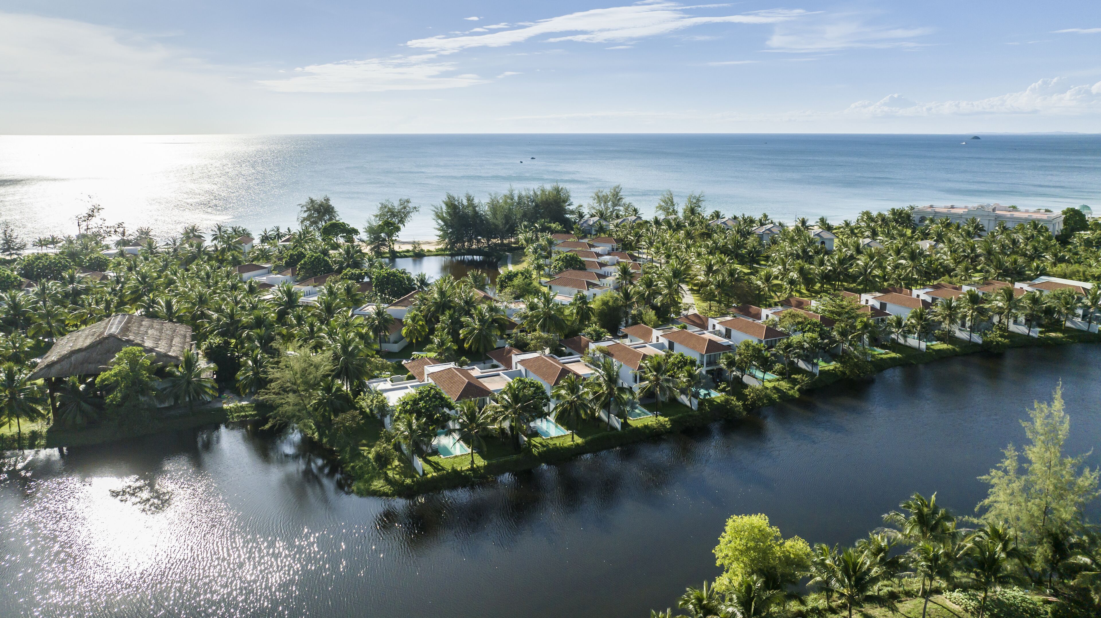 An aerial view of a coastal resort with villas, a marina, and a body of water.