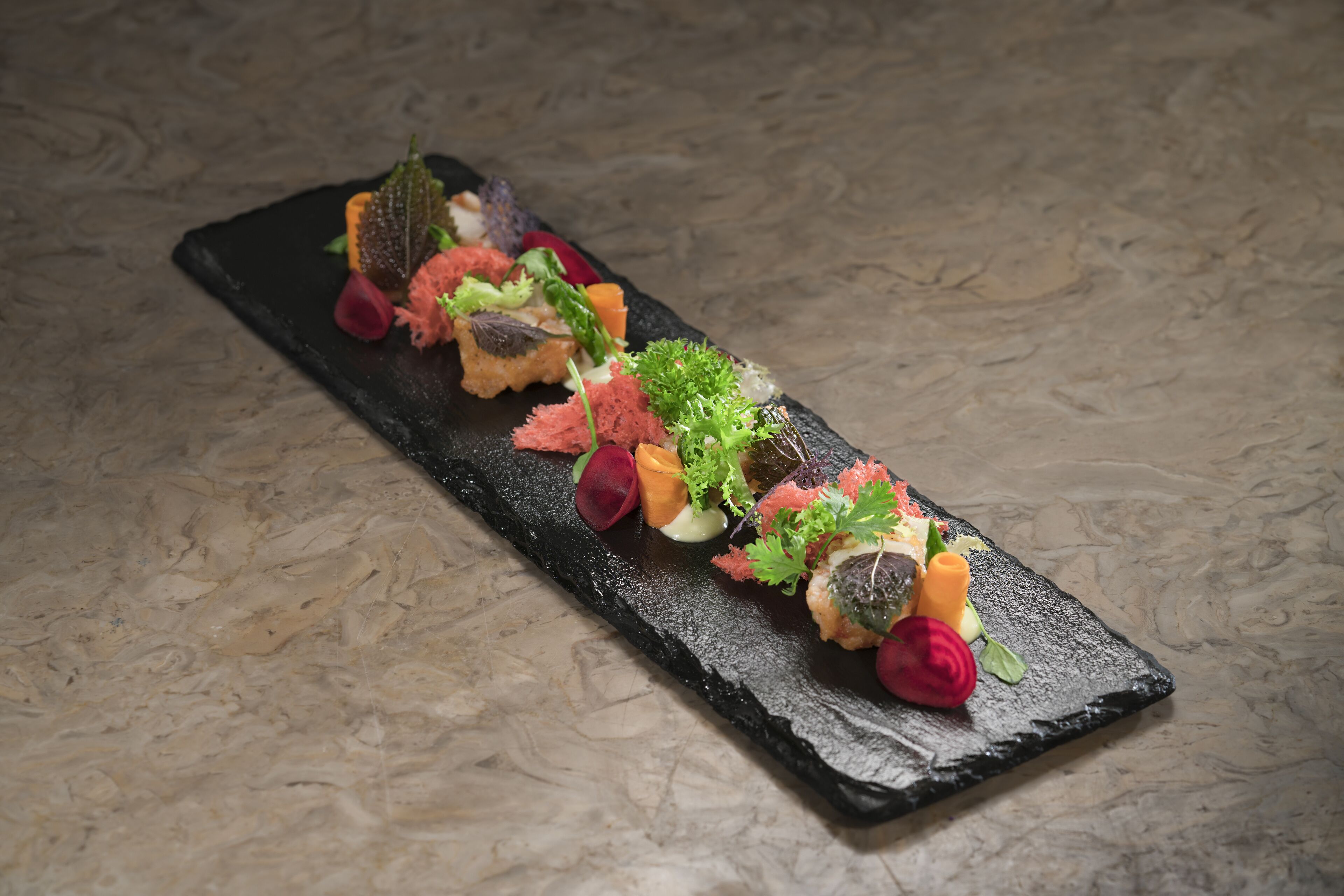 A black slate serving board with a variety of food items and garnishes.