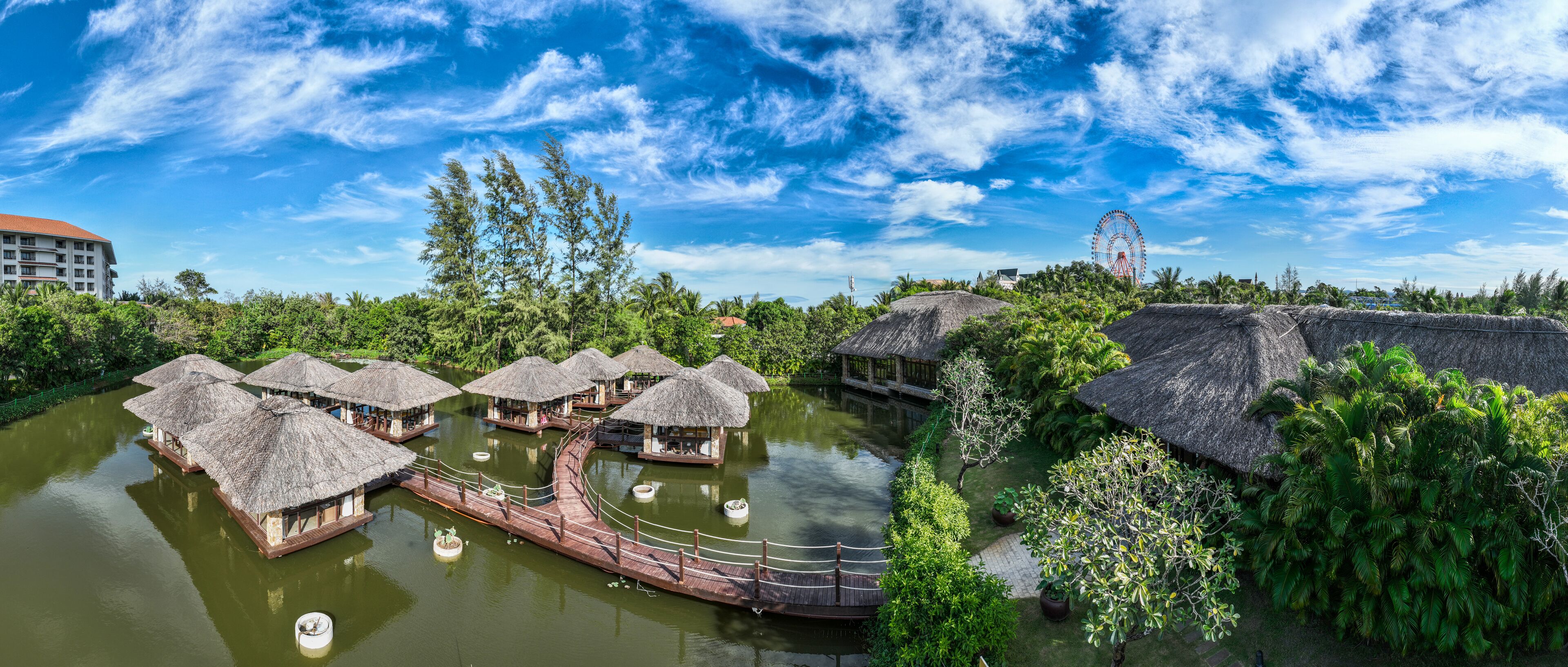 Bungalows sobre el agua con techos de paja, un puente de madera y un cielo azul cristalino.