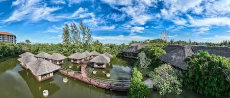 Bungalows sobre el agua con techos de paja, un puente de madera y un cielo azul cristalino.