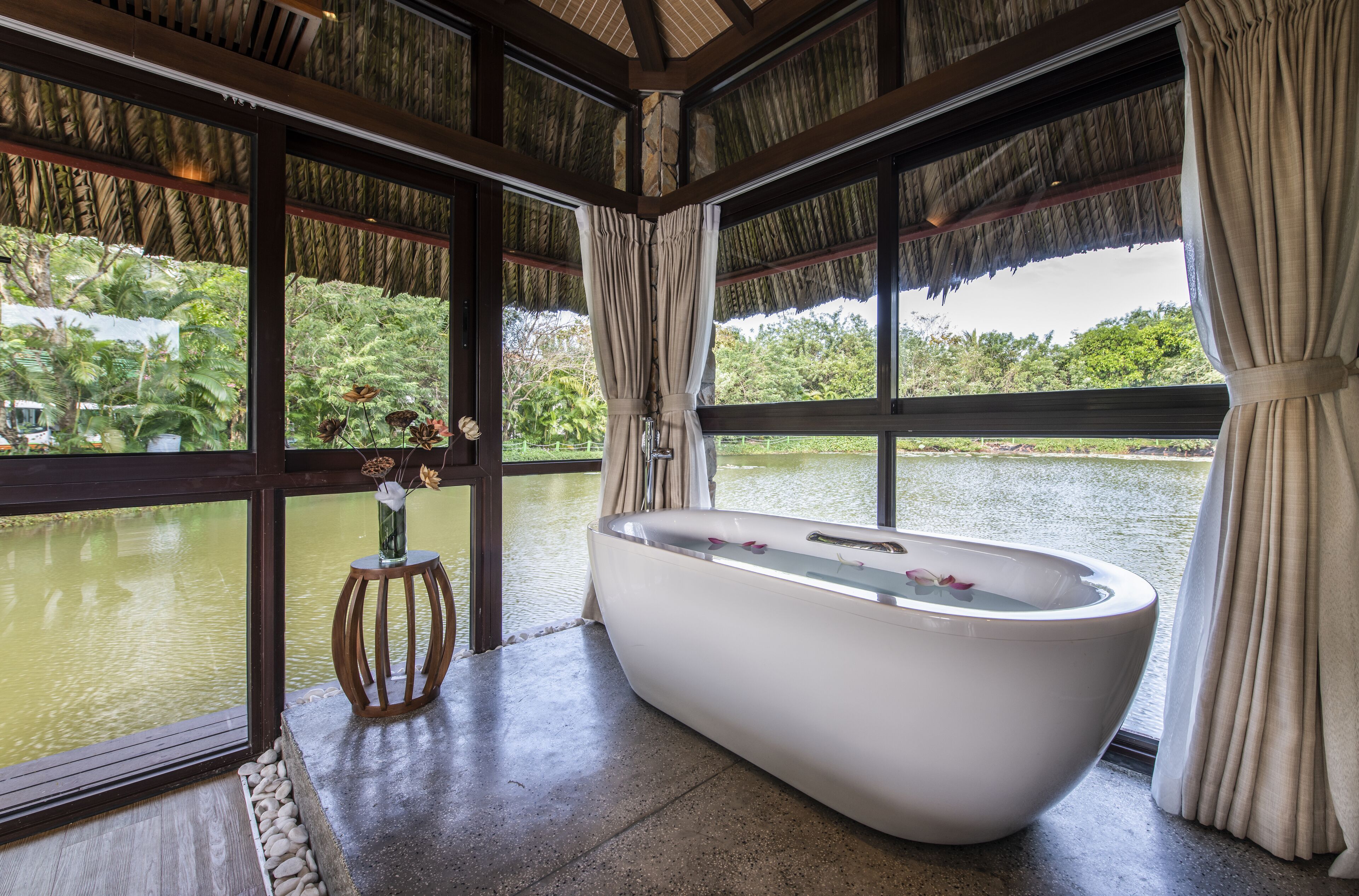 A large freestanding bathtub in a room with large windows overlooking a body of water.