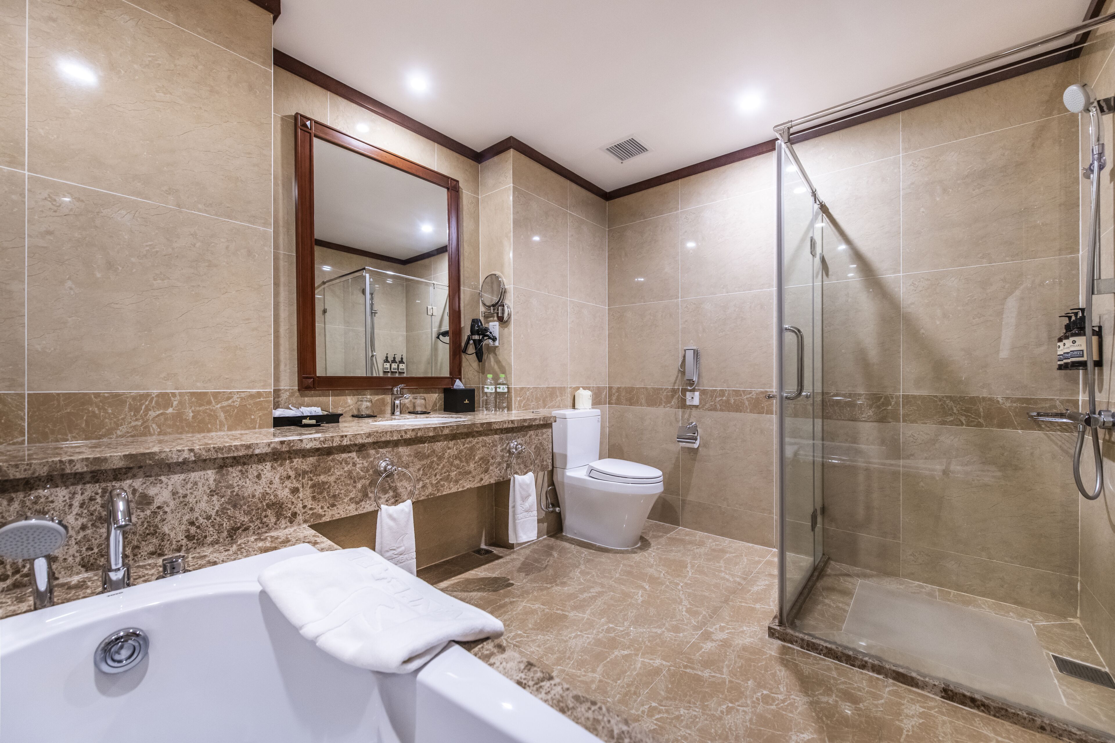 Un baño moderno con bañera, inodoro y ducha con mampara de vidrio.