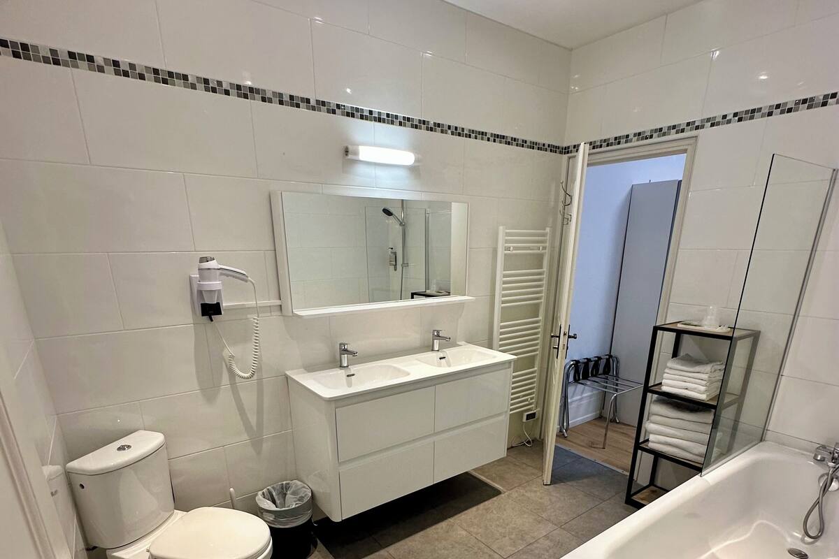 A modern bathroom with a toilet, bidet, sink, and bathtub.
