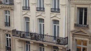Un immeuble à plusieurs étages, avec une enseigne d  ’hôtel bien visible, des balcons et des boutiques au rez-de-chaussée.