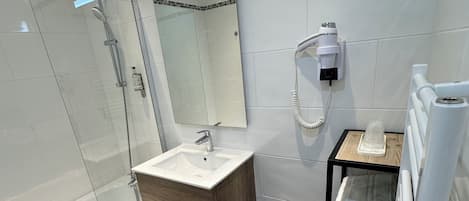 A modern bathroom with a glass-enclosed shower, a wooden vanity with a sink, and a towel rack.