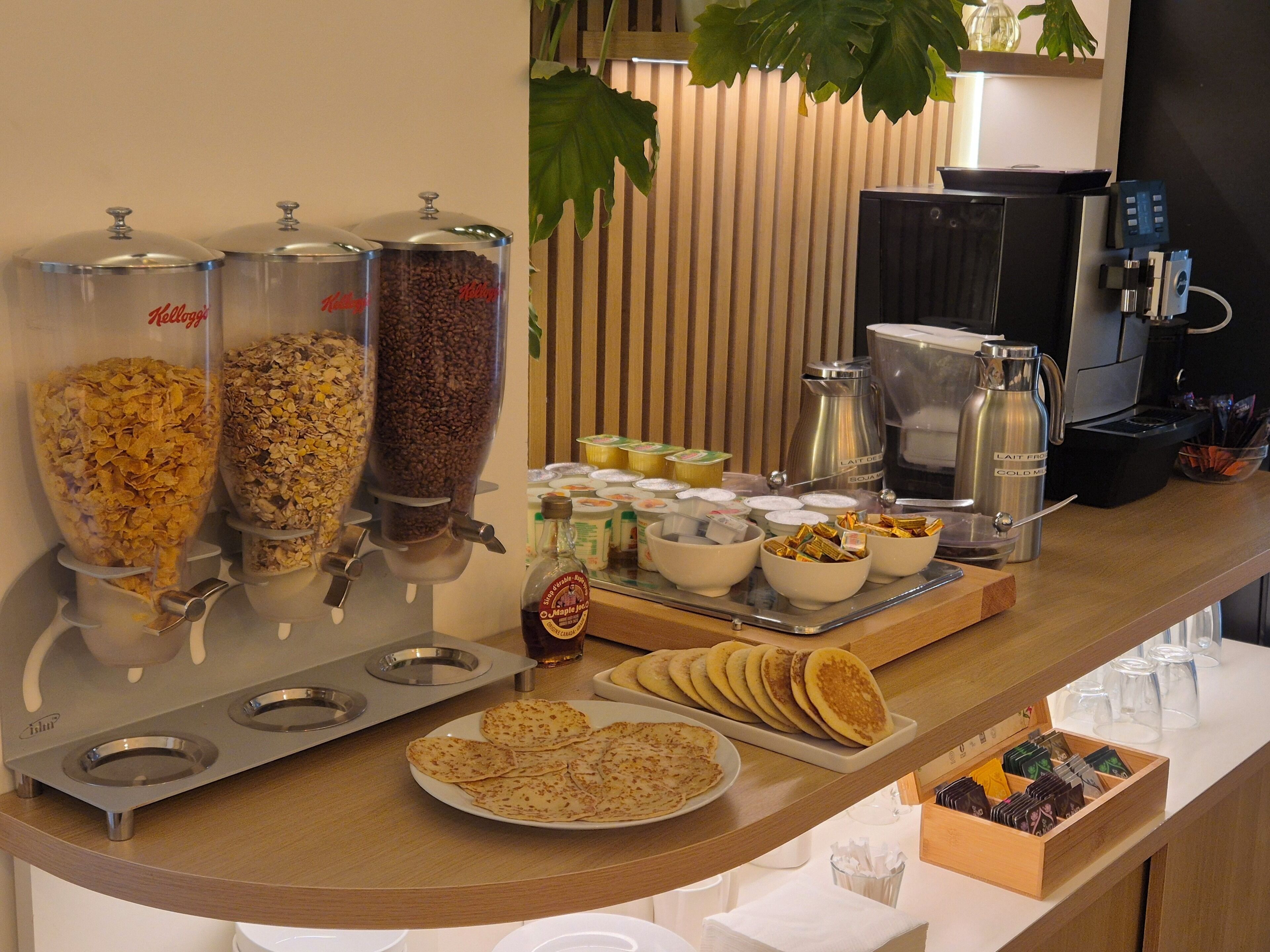 A breakfast buffet with cereal, oatmeal, and coffee options.