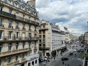 A street view of Parisian buildings with balconies, a visible storefront, and a busy street with cars and pedestrians. - Hôtel Océanic (Paris)