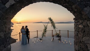 Un couple se tient dans une arche d’où l’on peut admirer un magnifique coucher de soleil.