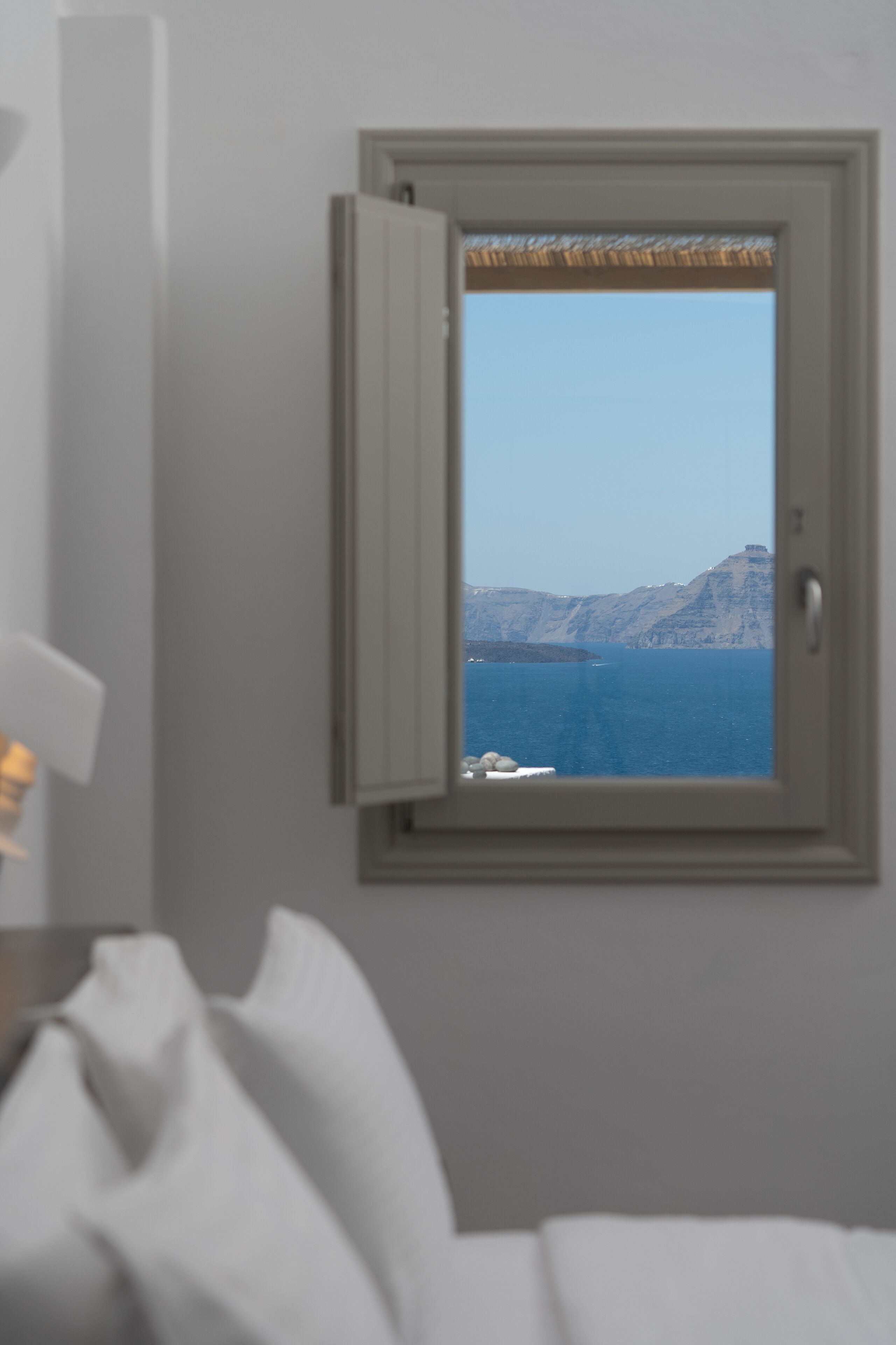 A window with a view of a mountainous coastline and the sea.