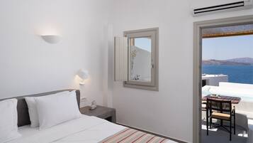 Ein Hotelzimmer mit Bett, Nachttisch, Spiegel und Meerblick.