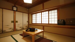 A traditional Japanese room with tatami flooring, shoji screens, a low table with a black pot, and a television on a wooden shelf. - Yumoto Onsen Oharasansou (Kyoto)