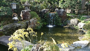 A serene garden with a small pond, rocks, and a waterfall. - Yumoto Onsen Oharasansou (Kyoto)