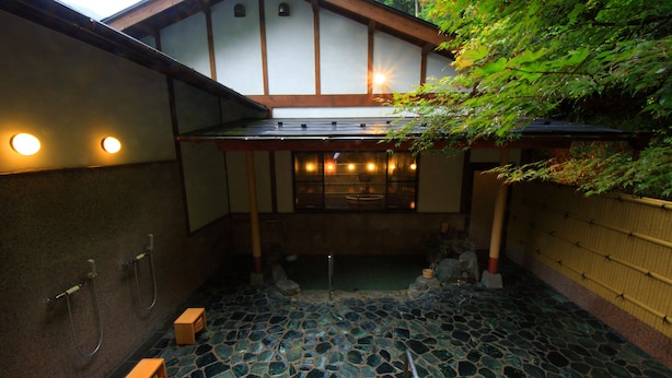 A traditional Japanese onsen with a stone mosaic floor, wooden beams, and a view of the surrounding nature. - Yumoto Onsen Oharasansou (Kyoto)
