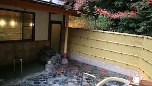 A traditional Japanese onsen with stone flooring, a hot spring tub, and a bamboo fence. - Yumoto Onsen Oharasansou (Kyoto)
