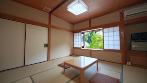 A traditional Japanese room with tatami flooring, a low wooden table, sliding doors, and a window with a view of greenery. - Yumoto Onsen Oharasansou (Kyoto)