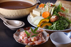A table with various dishes including a bowl of soup, a plate of vegetables, and a bowl of raw meat.