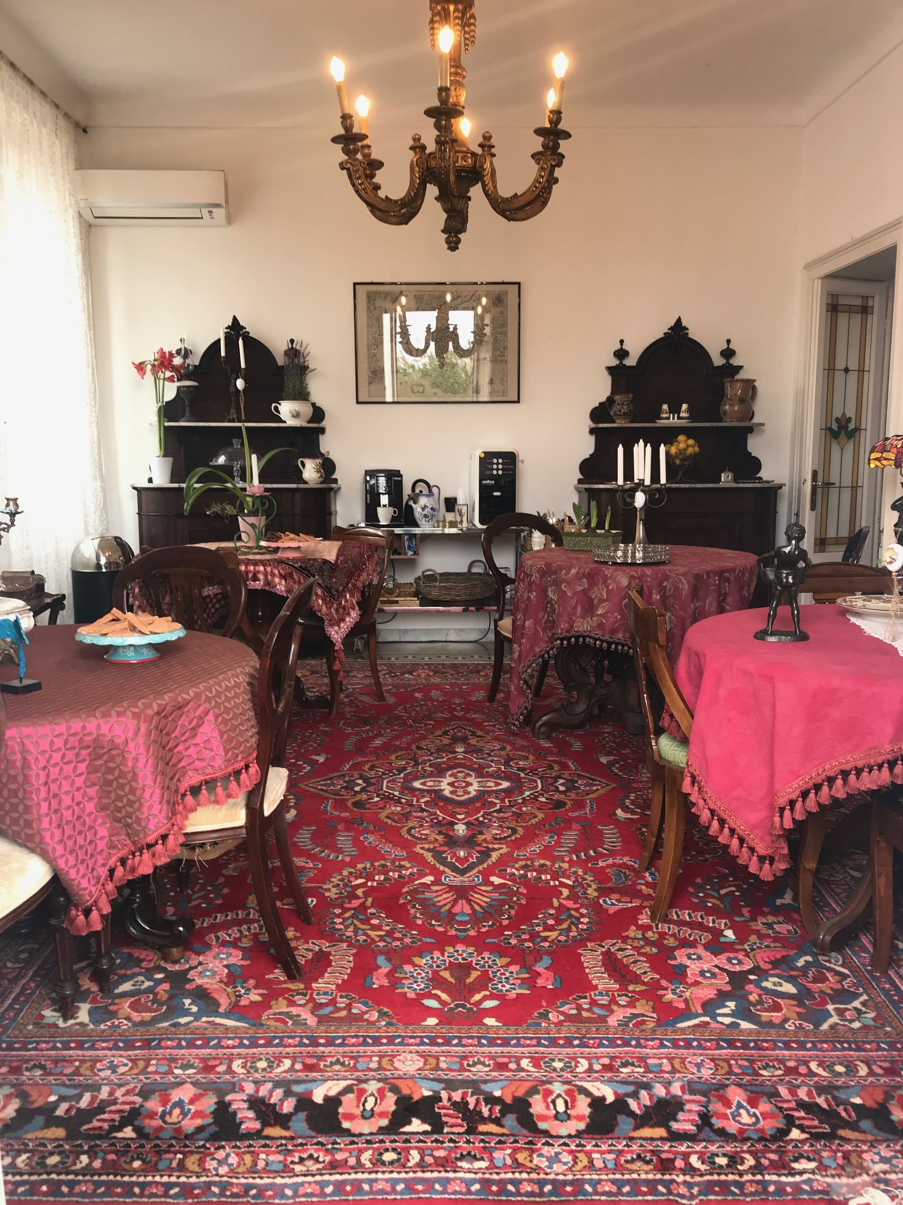 A traditional dining room with a red patterned carpet, wooden furniture, and a chandelier.