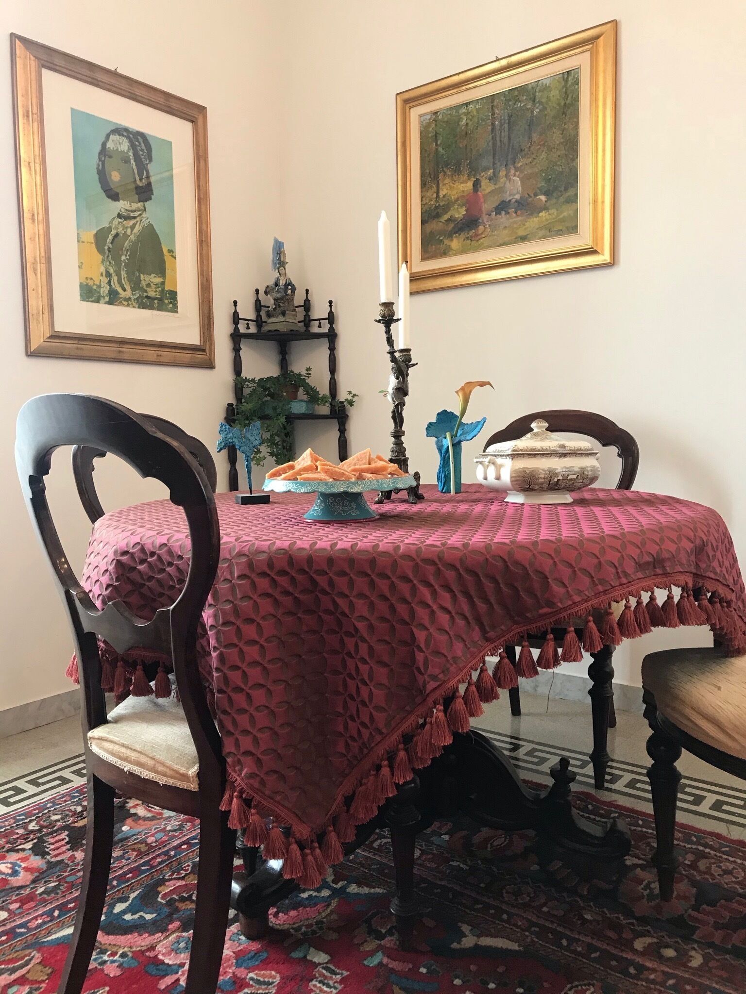Un coin repas avec une table recouverte d’une nappe à motifs, entourée de chaises en bois.