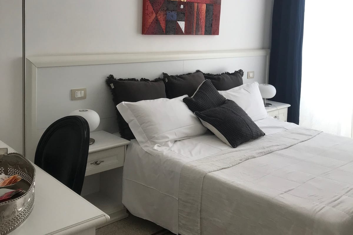Une chambre d’hôtel avec un lit, un bureau, une chaise, une lampe et un tableau au mur.