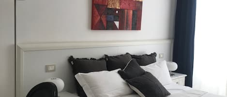 Una habitación de hotel con cama, escritorio, silla, lámpara y un cuadro en la pared.