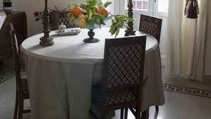 A dining area with a round table, chairs, a vase with flowers, and a framed picture on the wall. - B&B Nike (Syracuse)