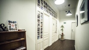 A hallway with a wooden shelf, a potted plant, and a door with an exit sign. - 360 Hostel Borne (Barcelona)