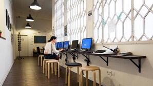A workspace with multiple computer stations, wooden stools, and a chalkboard on the wall. - 360 Hostel Borne (Barcelona)