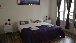 A neatly arranged bedroom with a bed, pillows, a nightstand with a lamp, and a window with curtains. - 360 Hostel Borne (Barcelona)