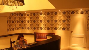 A room with a curved desk, patterned wallpaper, a wooden chair, and a closed door. - Vivaz Boutique Hotel (Recife)