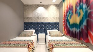 A room with two beds, a patterned headboard, and a tie-dye curtain. - Vivaz Boutique Hotel (Recife)