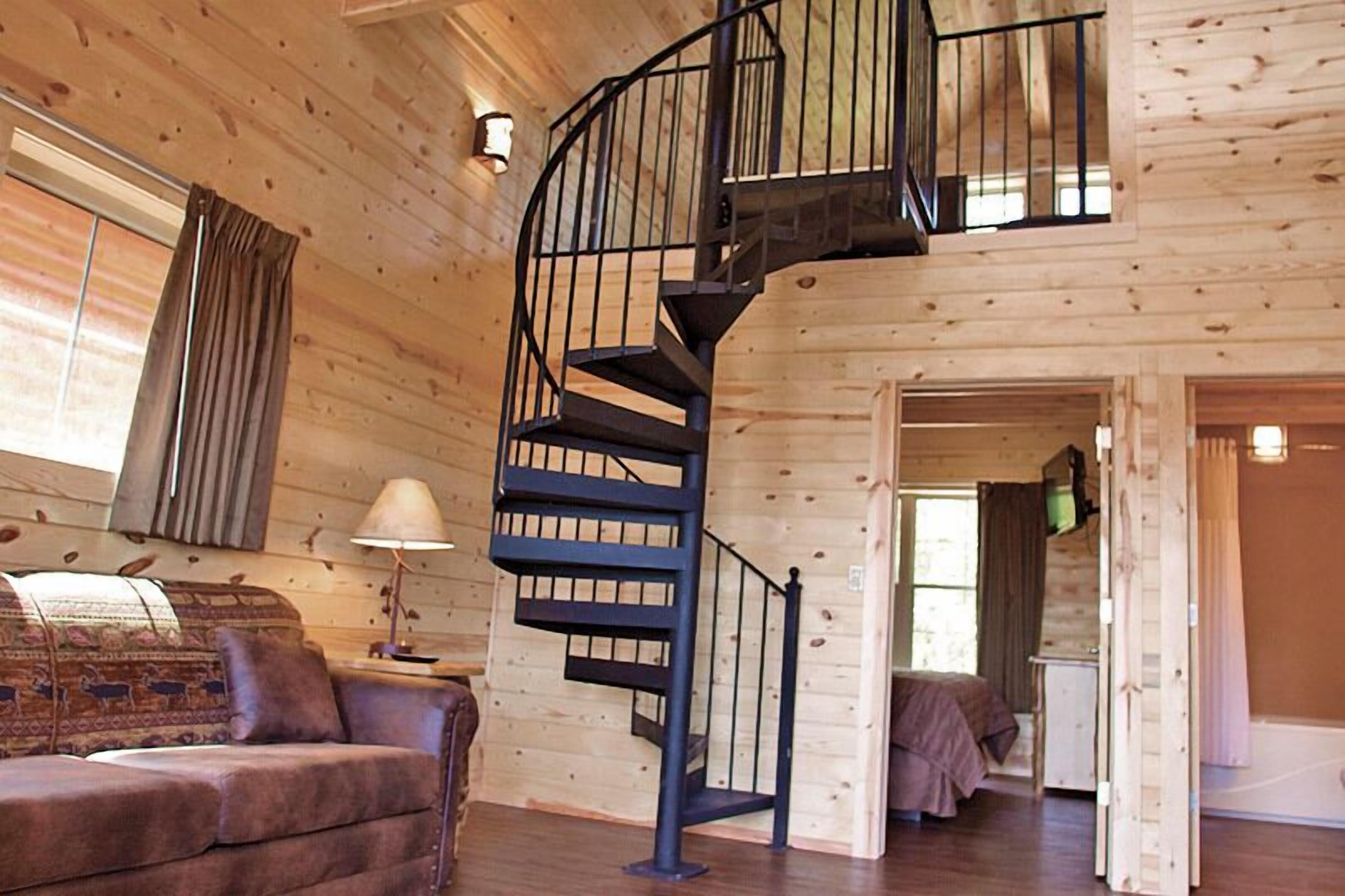Un intérieur en bois avec un escalier en colimaçon, un canapé et une lampe.