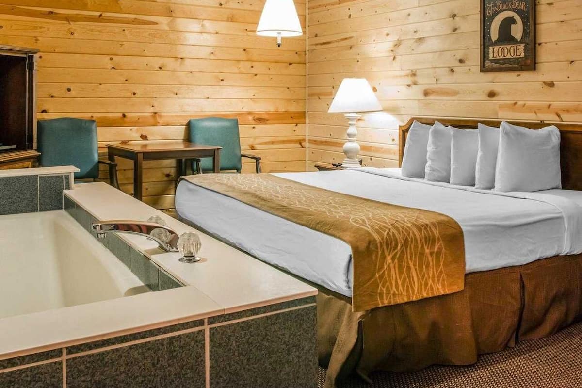 Une pièce confortable avec un lit, un bureau, une chaise et une baignoire.