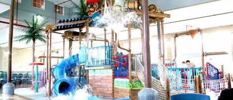 Parque acuático interior con toboganes, zona de juegos y piscina.