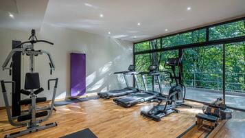 Een moderne fitnessruimte met cardioapparatuur, een halterbank en een yogamat.