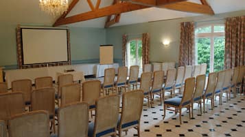 A conference room with rows of wicker chairs, a projector screen, and a chandelier.