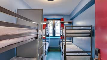 A narrow corridor with bunk beds on both sides, a door at the end, and a window with red curtains.