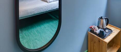 Una cama litera con un espejo, una mesita de madera con un hervidor y una decoración en forma de estrella en la pared.