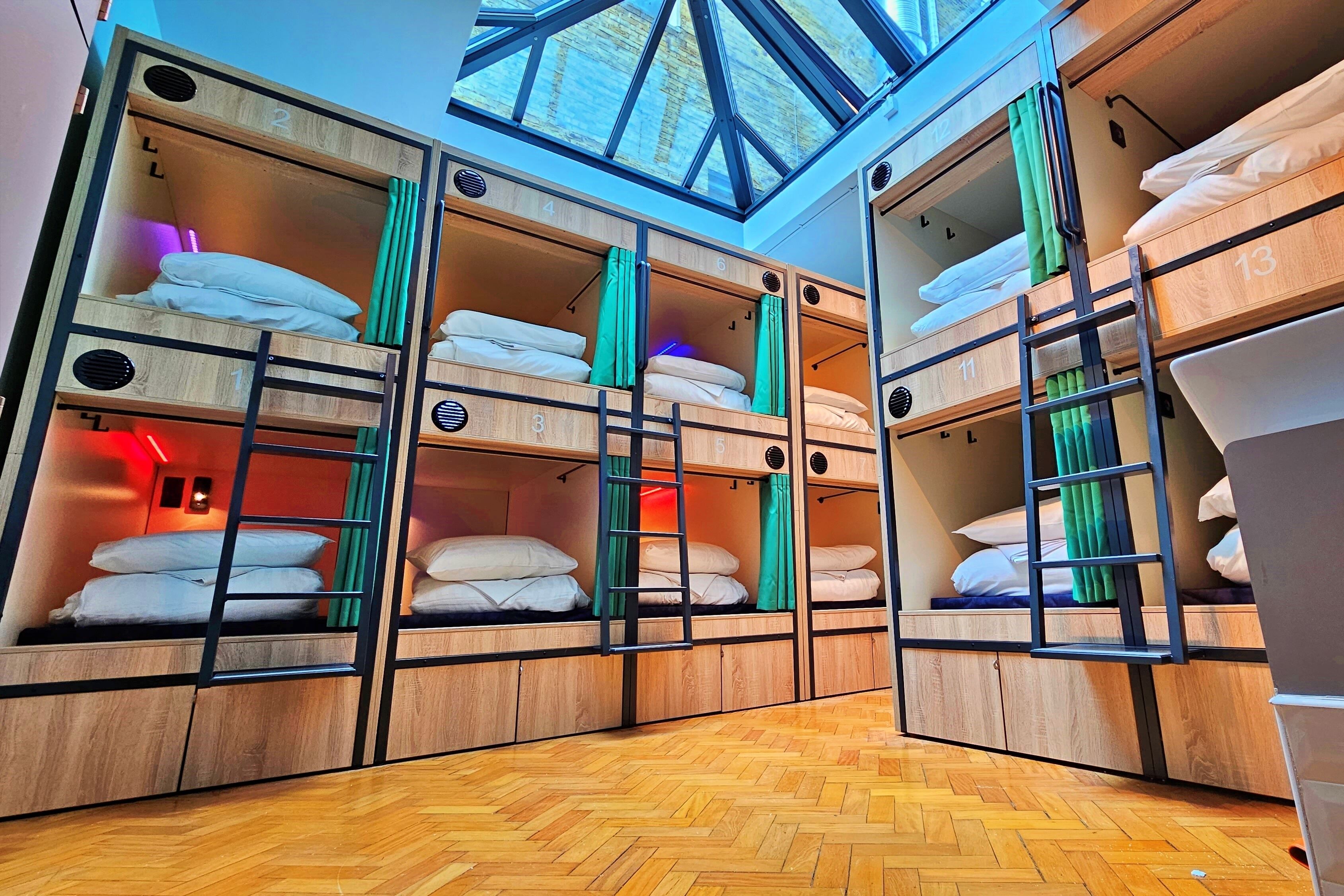 A multi-level bunk room with wooden bunk beds, each with a number label, and a skylight above.