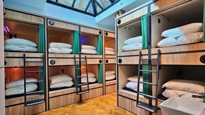 A dormitory-style room with bunk beds, numbered from 2 to 13, wooden flooring, and a skylight. - Clink 261 Hostel (London)