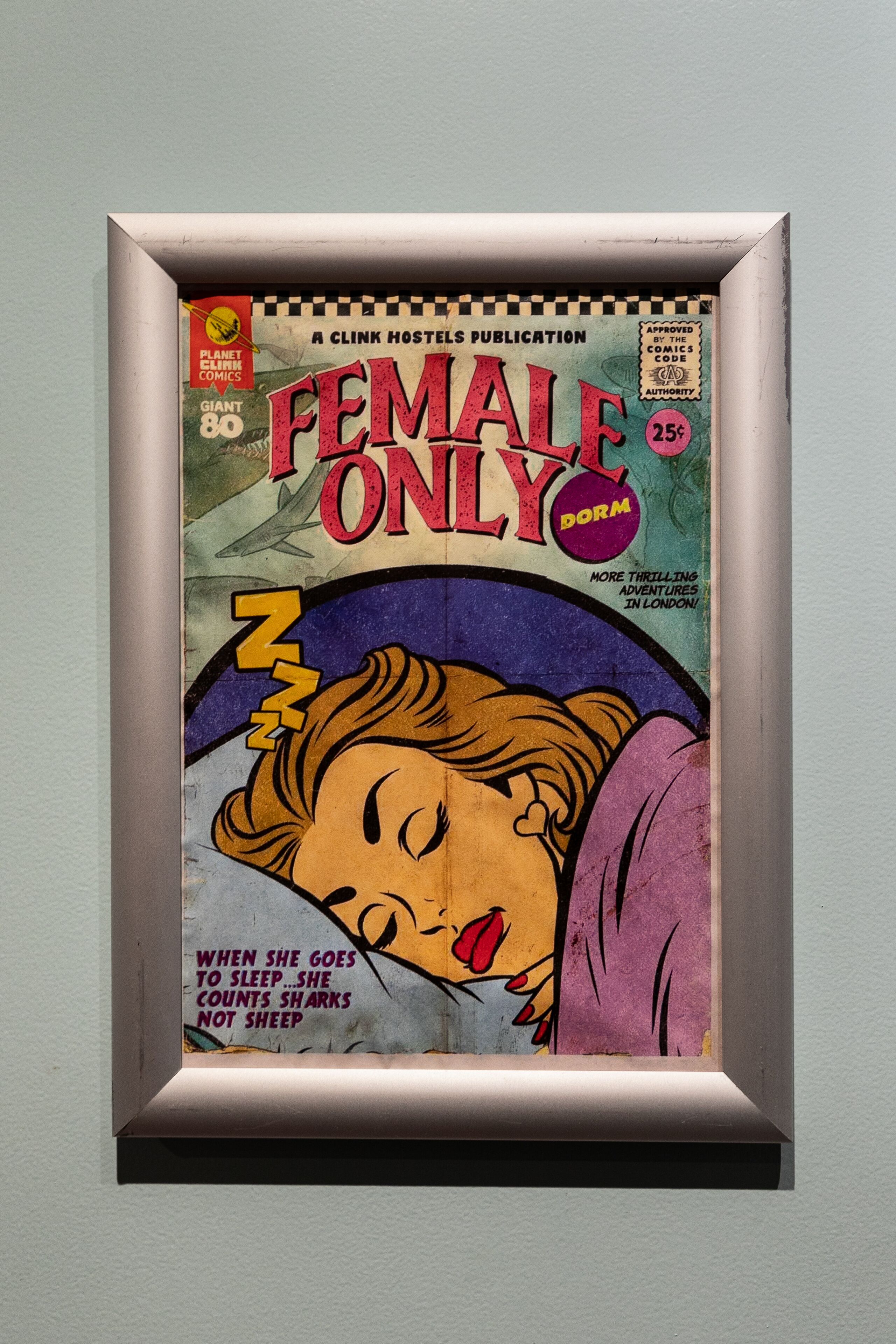 Une bande dessinée encadrée, intitulée « FEMMES SEULEMENT », dont la couverture représente une femme endormie.