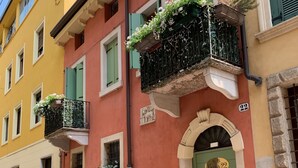 A building with a green door, a balcony with flowers, and a number '22' sign. - Vicolo 22 (Verona)