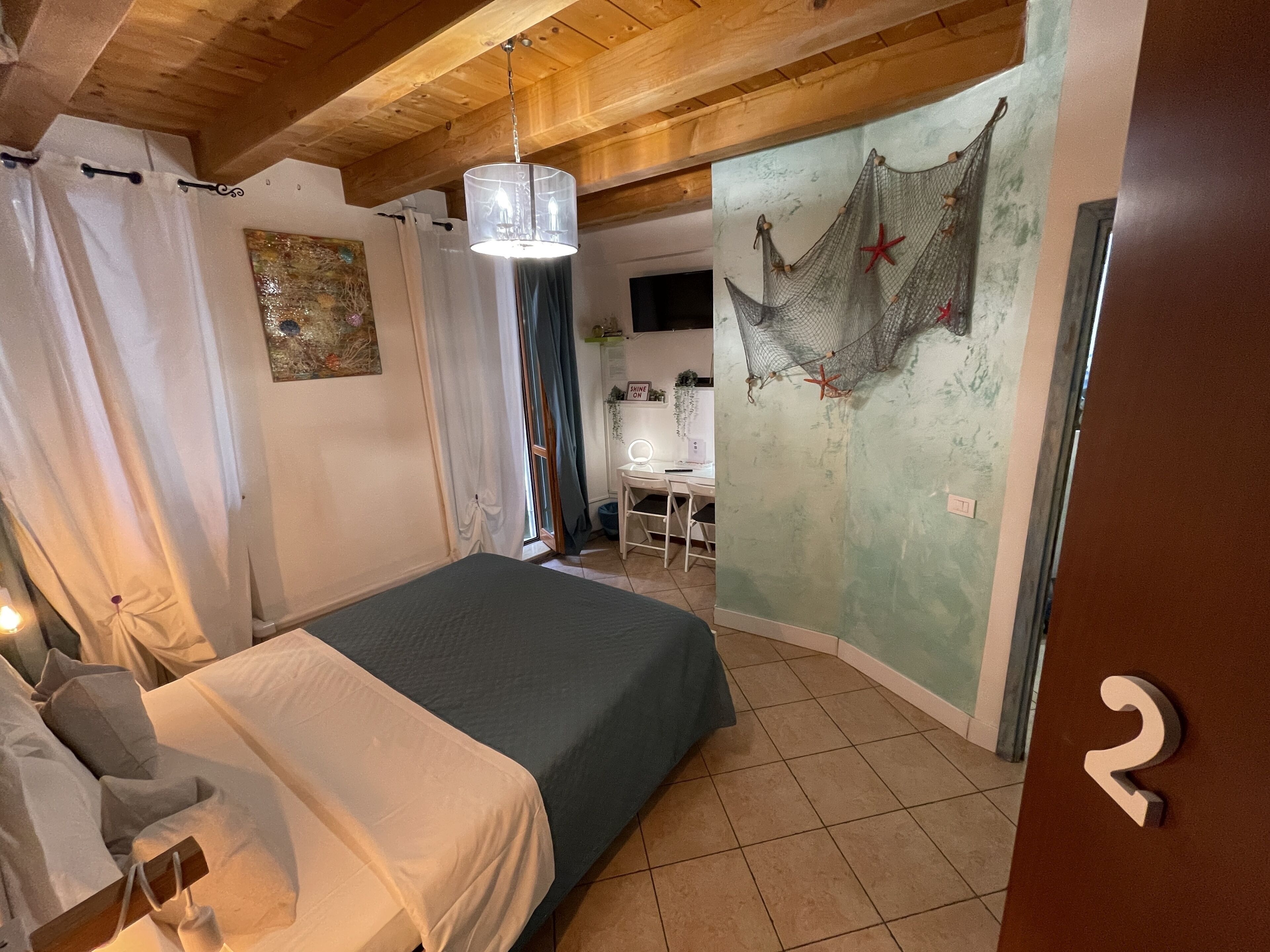 A bedroom with a bed, a desk, and a wall with a nautical theme.