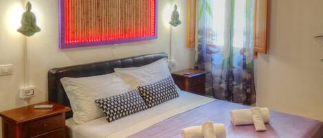 A bedroom with a bed, wooden headboard, bedside tables, and a wall-mounted light fixture.