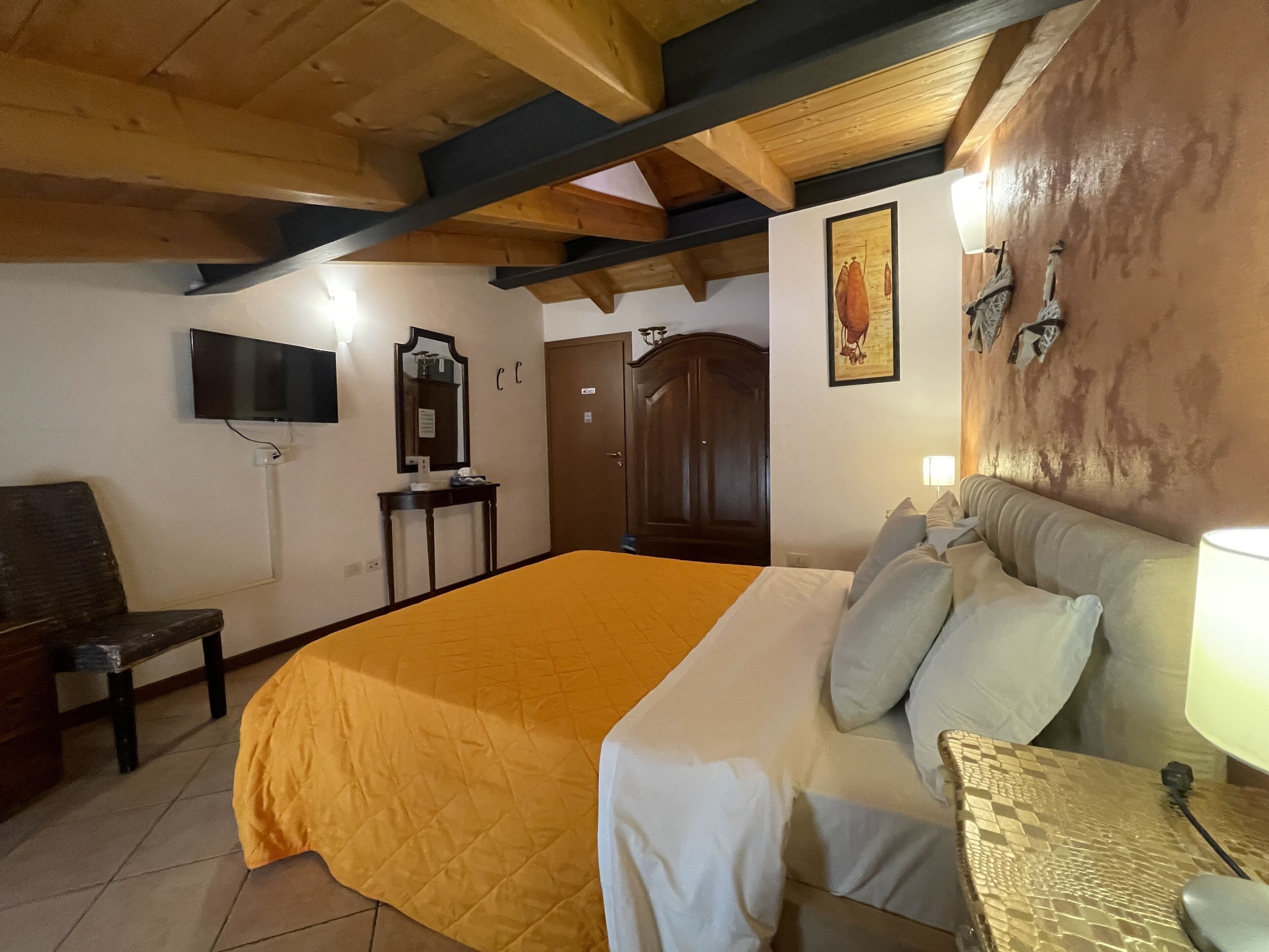 A hotel room with a bed, a desk, a chair, a television, and a wardrobe.