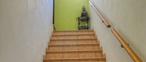 A staircase with a handrail, leading to a room with green walls and a small statue.