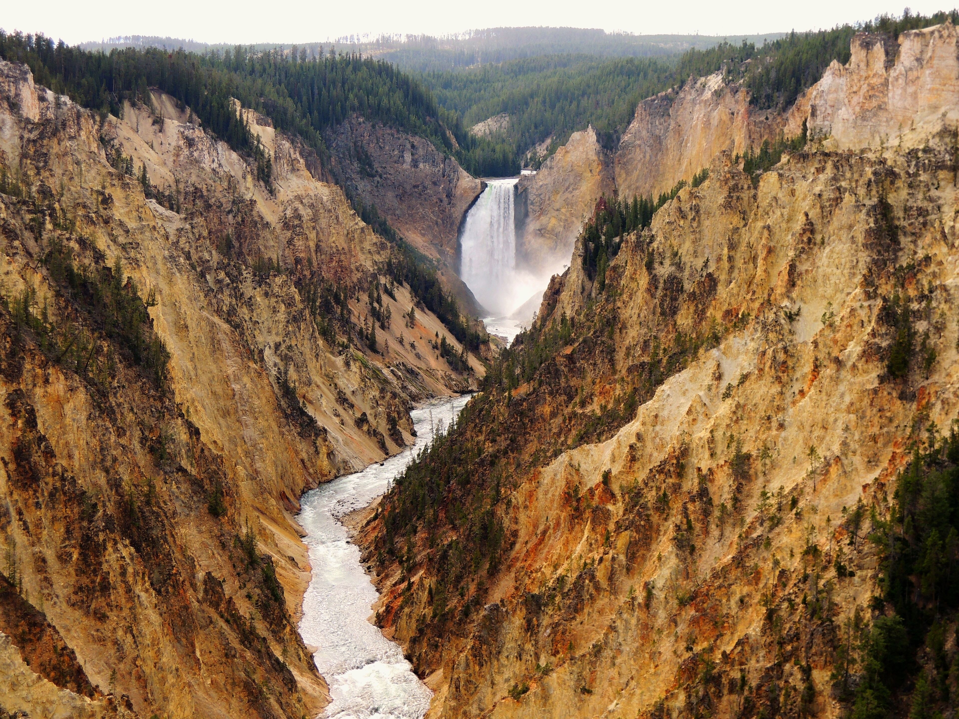 A canyon with a river flowing through it and a waterfall in the distance.