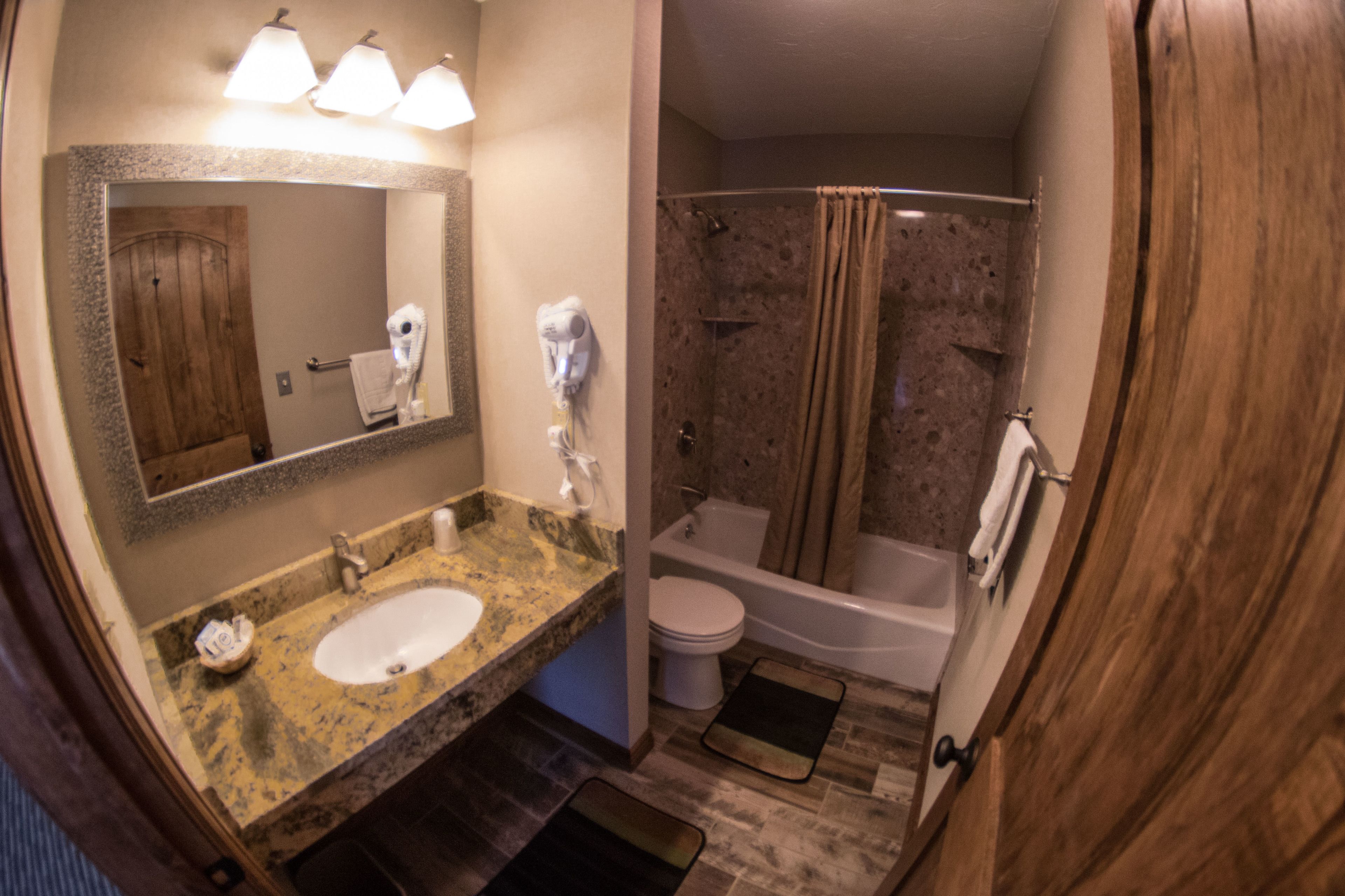 Ein Badezimmer mit Waschbecken, Spiegel, Handtuchhalter, Dusche und Toilette.