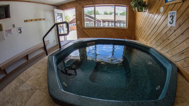 A hot tub in a room with wooden walls, a window, and a sign indicating a spa depth of 3 feet.